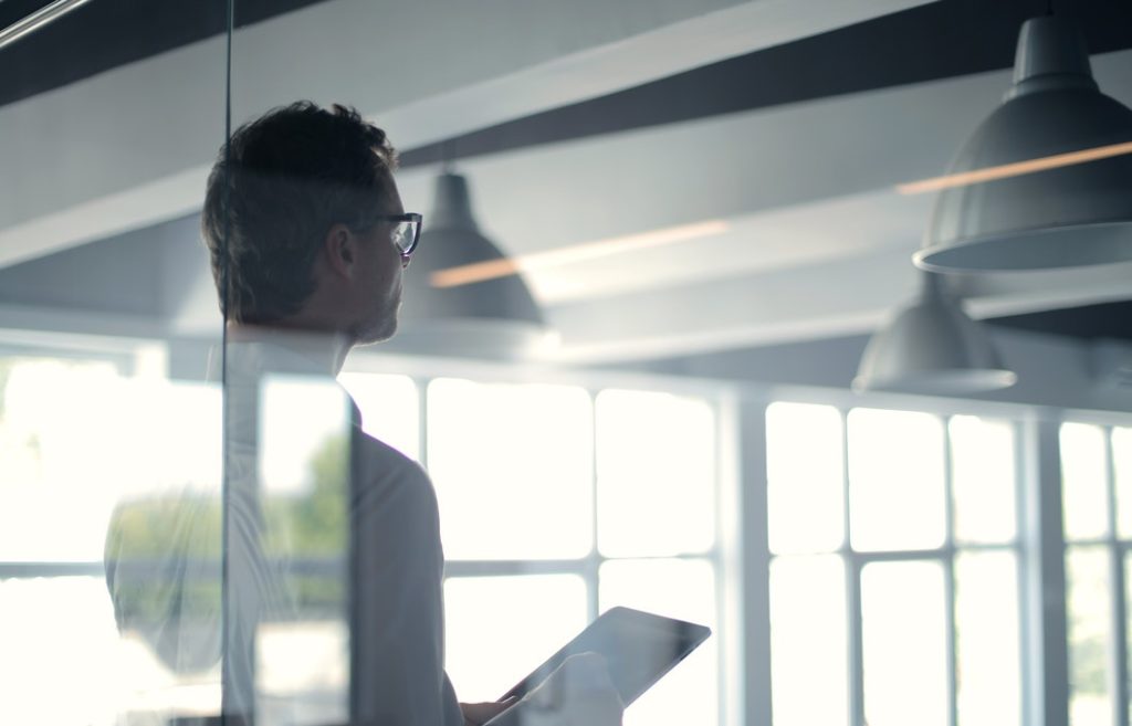 Man with tablet performing risk evaluation for a property in light-filled room.